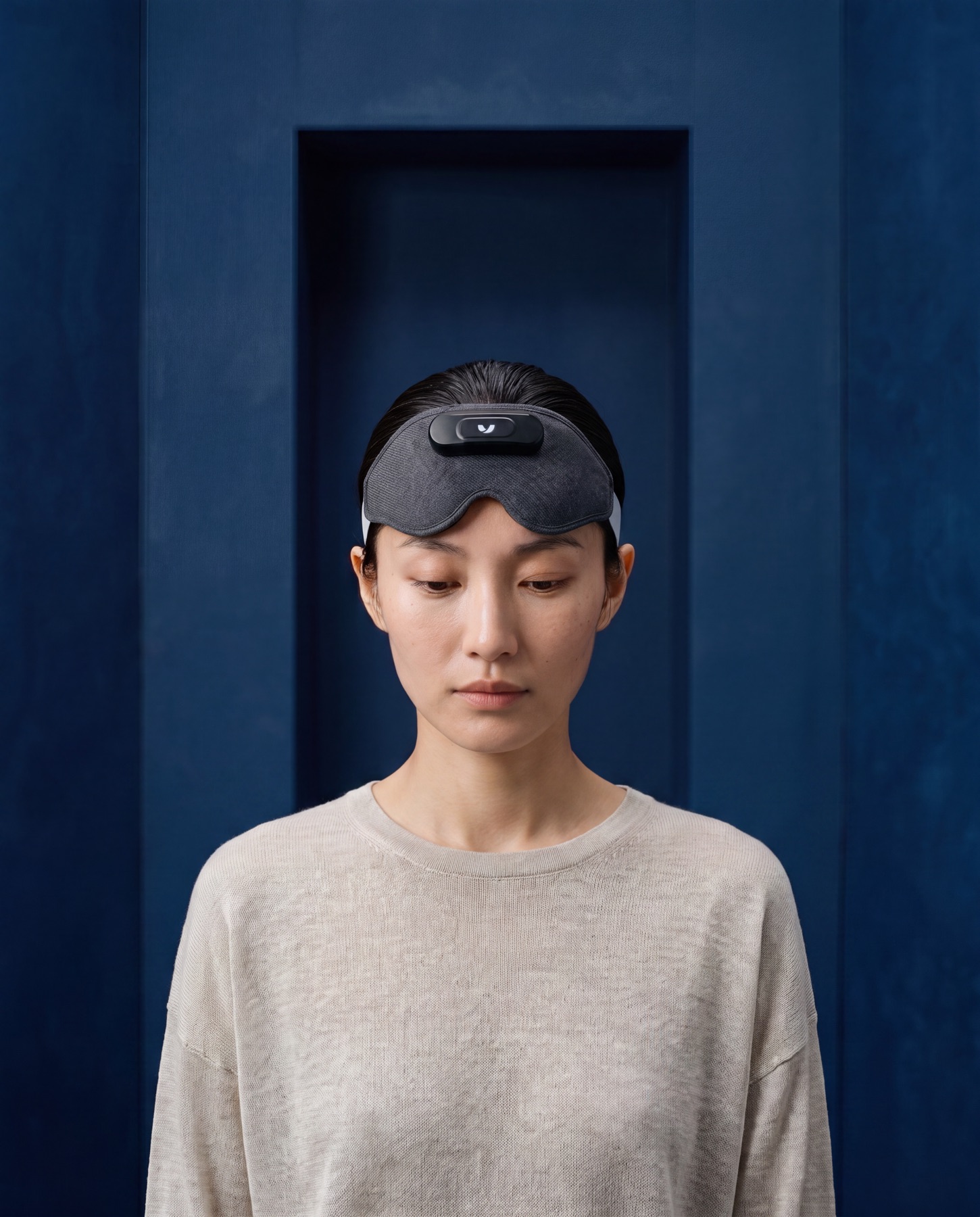 一位梳着后背头的女性，将 Mask 推至额前，垂目而立，身处深蓝色巨石般的空间中